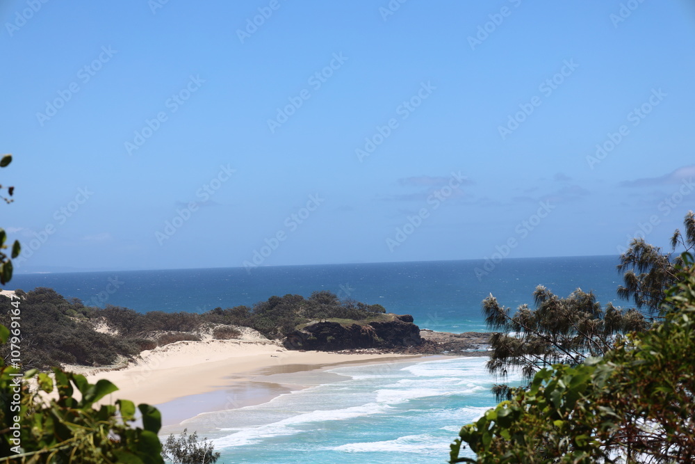 Naklejka premium blue sky, deep blue sea, forested shores and sandy beach