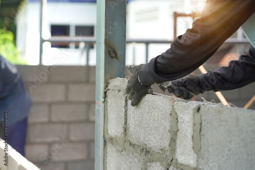 The builder places the block during the construction of the wall