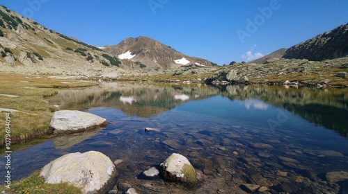 A serene mountain landscape with a clear lake reflecting the sky and surrounding peaks.