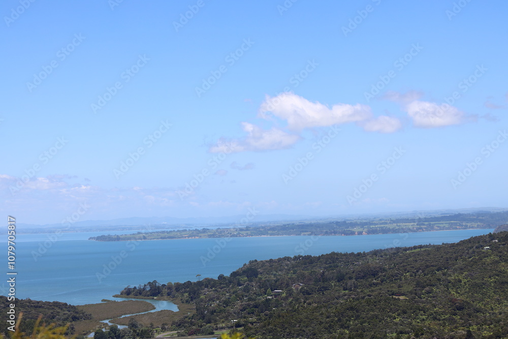 Obraz premium blue ocean bays and green forested lands under blue sky and fluffy white clouds
