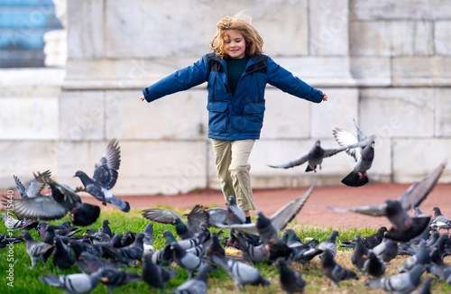 Happy child chasing birds on autumn day. Child run for pigeons. Carefree kids concept. Happy childhood. A Happy child chases pigeons in park. Happy Child playing with doves. Carefree Kid run pigeons. photo