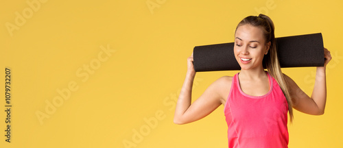 Portrait Of Sporty Young Woman With Fitness Yoga Mat Behind Her Head On Yellow Background With Copy Space photo