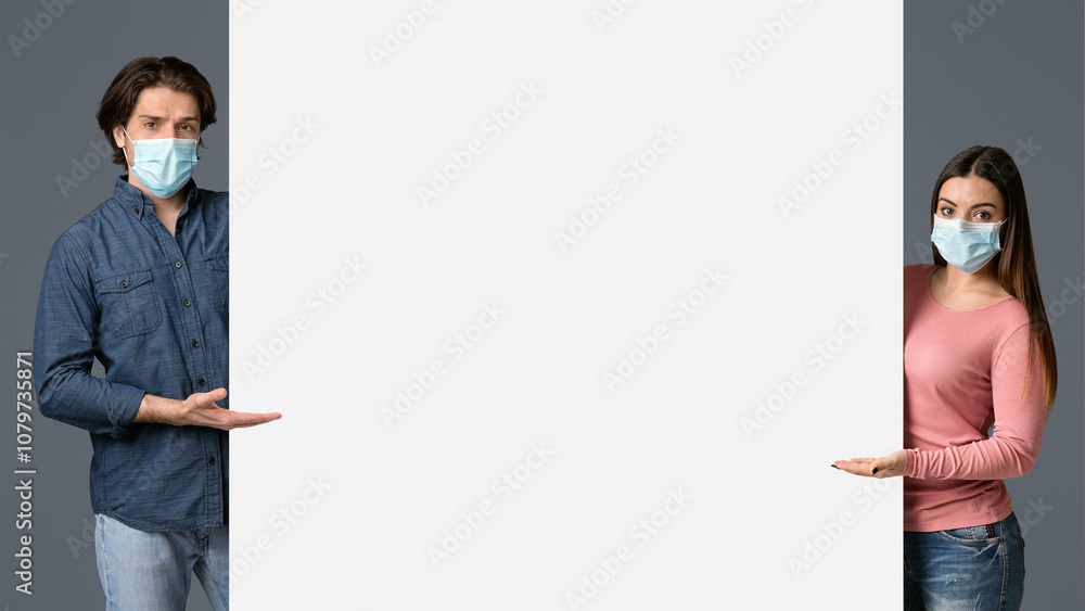 Young Couple In Medical Masks Pointing At White Advertisement Board With Open Palms, Standing Together Over Light Background, Free Place For Your Text Young Couple In Medical Masks Pointing At White Advertisement Board With Open Palms, Standing Together Over Light Background, Free Place For Your Text