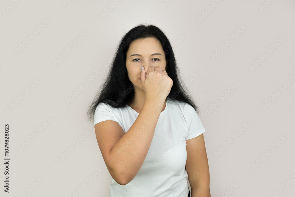 Portrait of a young woman holding her nose because of a bad smell. Portrait of a young woman holding her nose because of a bad smell.