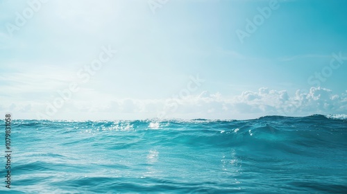 Bright and Tranquil Ocean Waves Under a Clear Blue Sky Reflecting Gentle Sunlight with Soft Clouds in the Distance for Serene and Calming Coastal Imagery