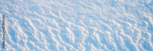 Beautiful winter background with snowy ground. Natural snow texture. Wind sculpted patterns on snow surface. Wide panoramic texture for background and design.