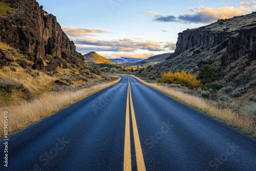 A winding road leads through a canyon at sunset.