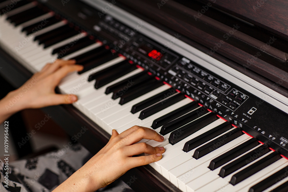 Obraz premium Close-up image of child's hands playing digital piano at home