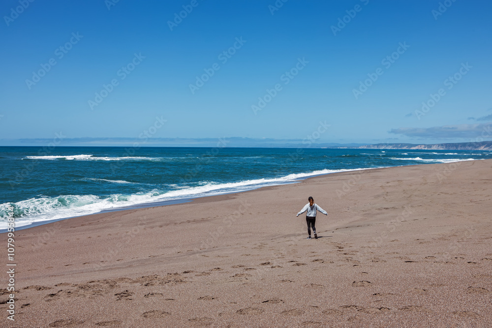 Woman enjoying empty beach near Pacific ocean, view from the back Woman enjoying empty beach near Pacific ocean, view from the back