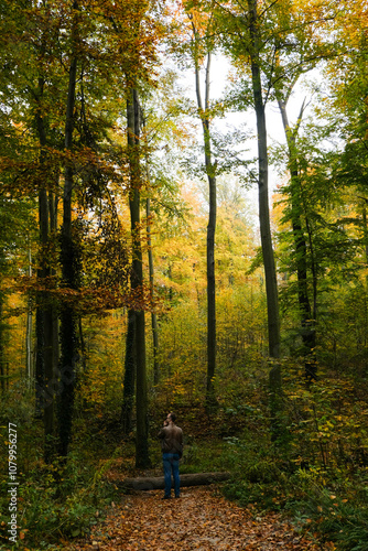 Young mang standing in a middle of autumn forest photo