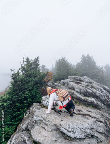 Female hiker climbing mountain trail on a foggy day photo