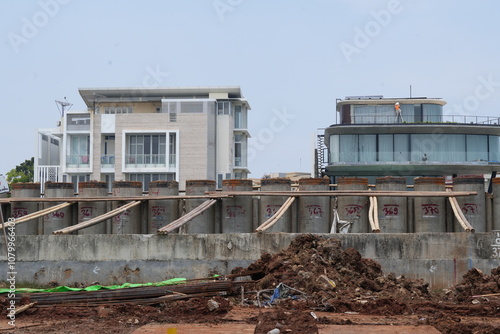 Lava rock breakwater sea wall with foggy sky background. and workers building. coastal area for erosion control. photo