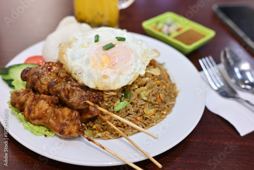 Indonesian fried rice with chicken satay and sunny side up egg on top photo