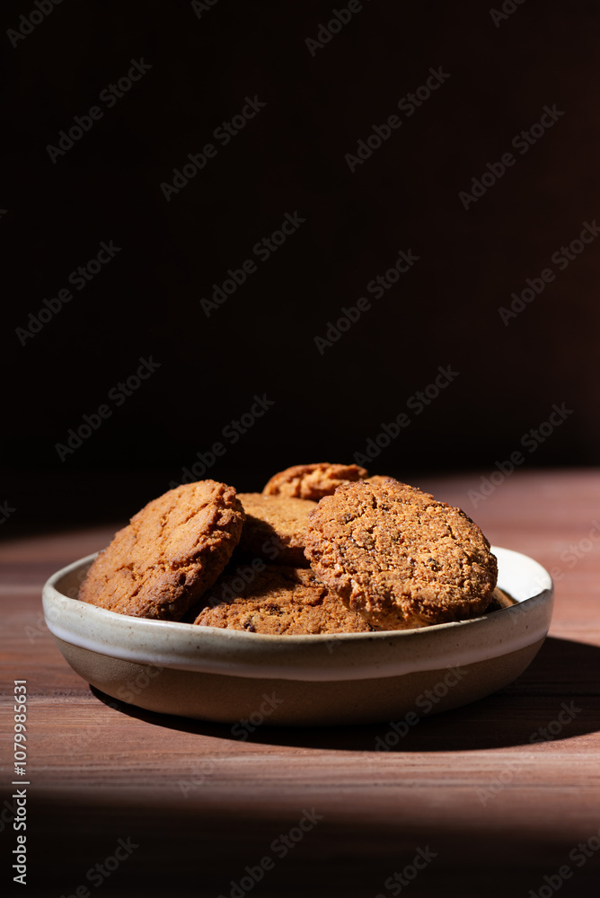 Oatmeal cookies tasty breakfast in the plate on a wooden table. Hard light. Vertical orientation. Oatmeal cookies tasty breakfast in the plate on a wooden table. Hard light. Vertical orientation.