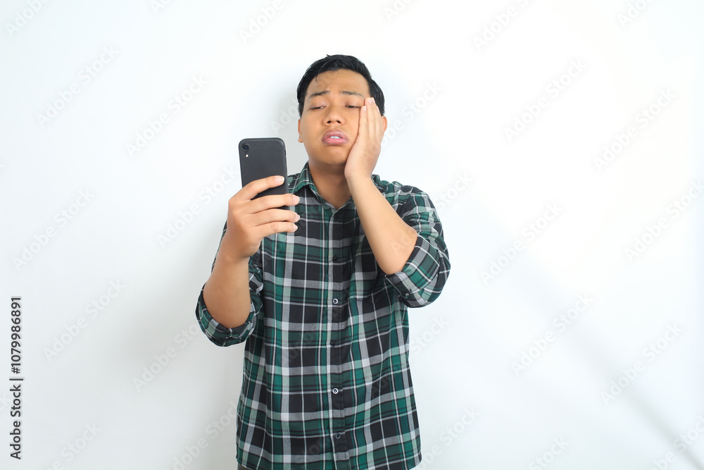 asian man suffering tootache while talking on smartphone isolated on white background asian man suffering tootache while talking on smartphone isolated on white background