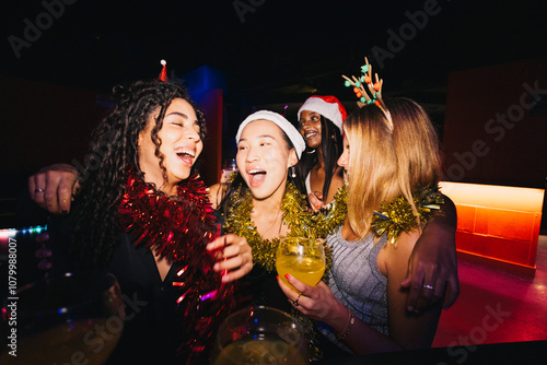 A group of friends celebrating together at a christmas party in a night club. They're wearing festive accessories and sharing joyful moments with drinks.