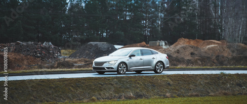 Silver car driving near construction site