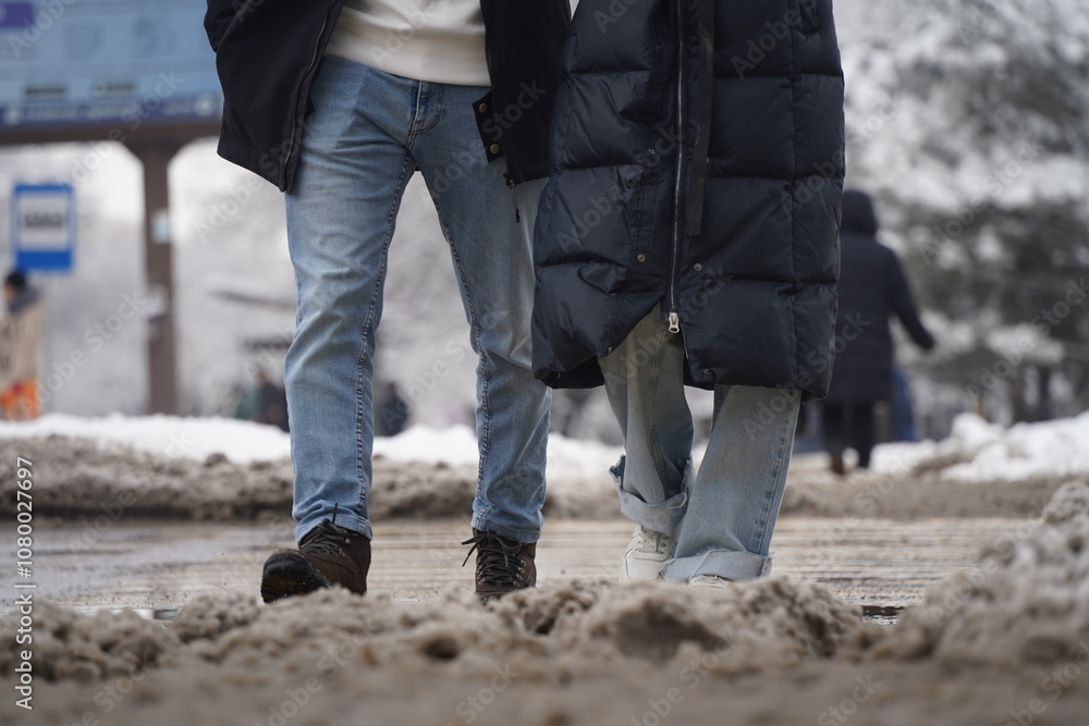 People walk through the wet dirty snow on the street. People walk through the wet dirty snow on the street.