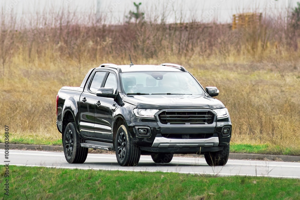 Sleek black pickup driving on a suburban road Sleek black pickup driving on a suburban road