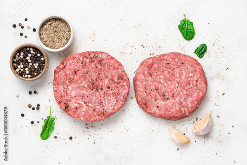 Raw piece of steakburger on marble board with spices. Marbled beef for making burger photo