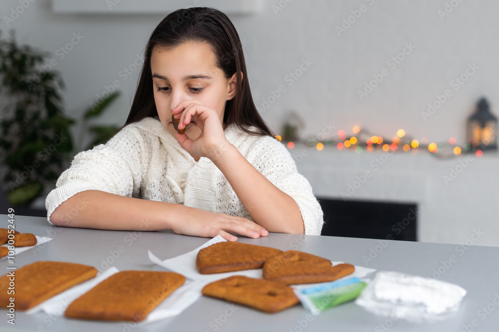 Kids baking Christmas gingerbread house. Children celebrating winter holiday at home. Decorated living room with fireplace and tree. Family activity. Little girl making cookies Kids baking Christmas gingerbread house. Children celebrating winter holiday at home. Decorated living room with fireplace and tree. Family activity. Little girl making cookies