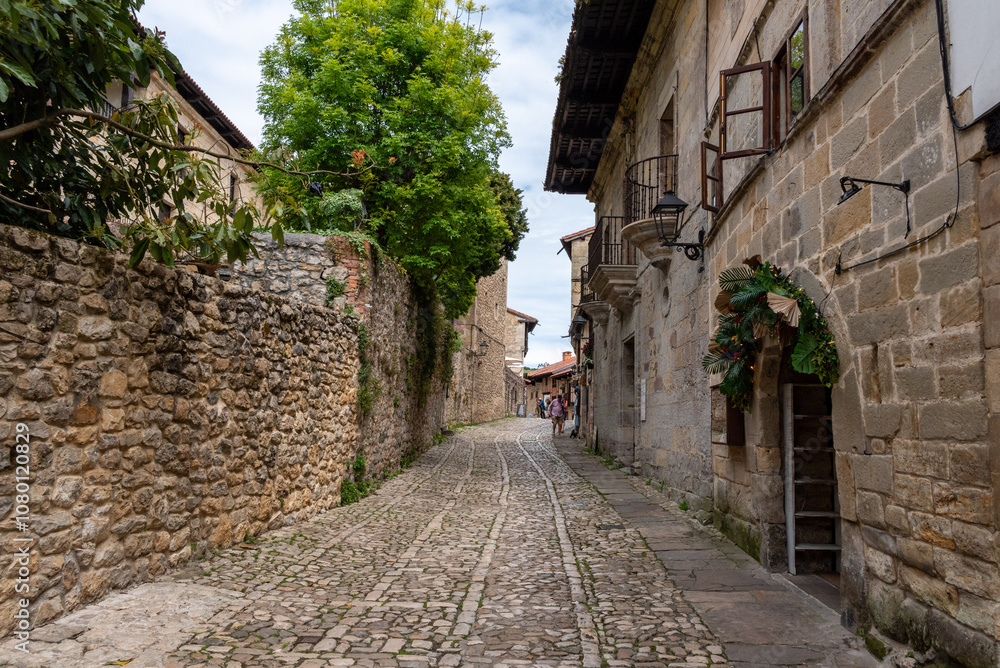 Obraz premium Empty cobblestone street surrounded by ancient houses and a stone wall in the medieval little town Santillana del Mar, Cantabria region