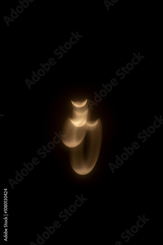Multiple exposures of the crescent moon layered together, forming an abstract, looping figure in the dark sky, with soft golden light trails conveying motion and time-lapse.