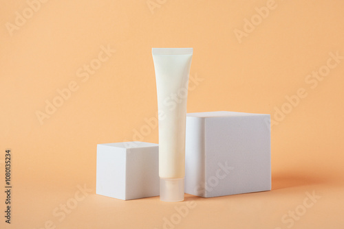 Plastic white tube for cream or lotion. Skin care or sunscreen cosmetic with stylish props on cream background.