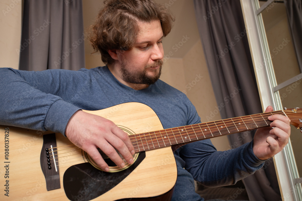Obraz premium Man Practicing Guitar in Cozy Bedroom, guitarist embracing melody and rhythm