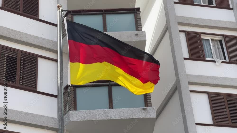 Close-up of the German flag waving against the backdrop of a modern building, symbolizing national pride and identity.
