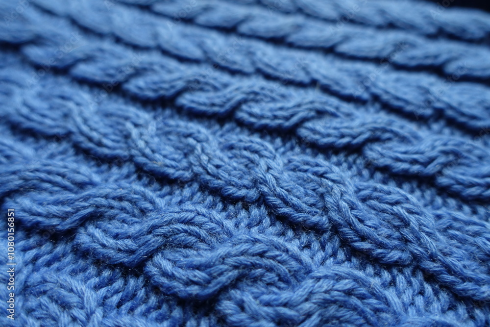 Closeup of handmade blue knitted fabric with cable braids Closeup of handmade blue knitted fabric with cable braids