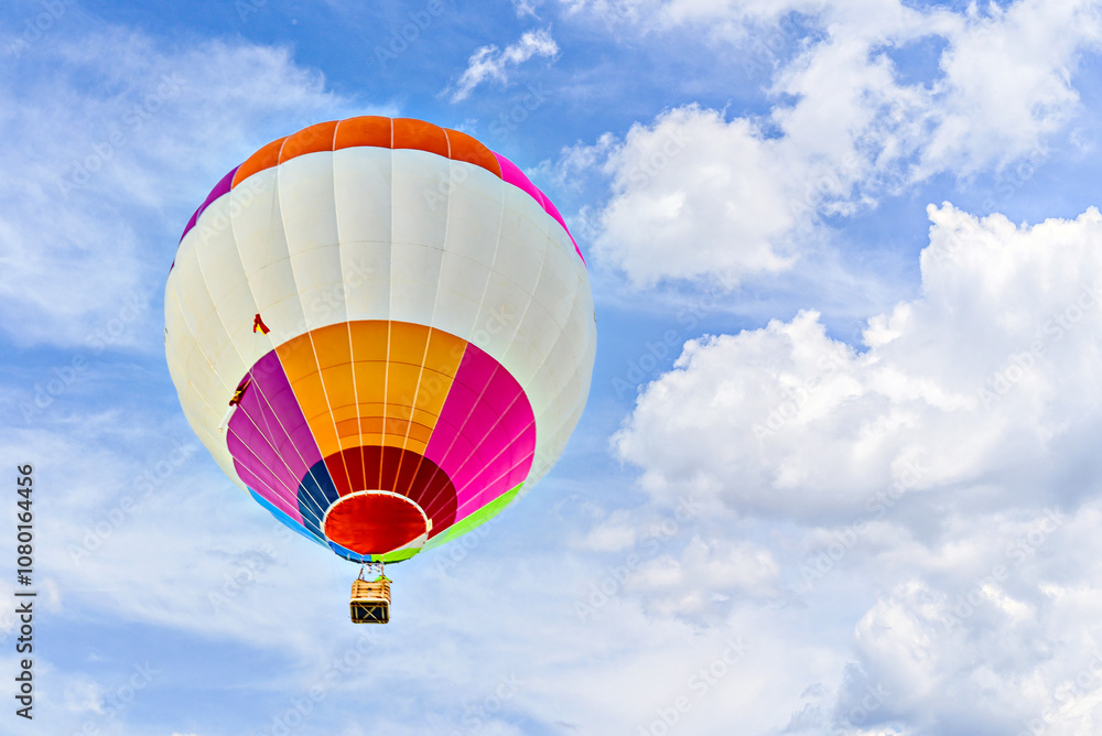 Fototapeta premium Colorful hot air balloon flying over blue sky with white clouds 