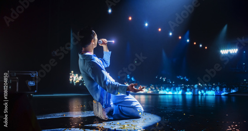 Pop Artist Performing Live Concert on Stage, Illuminated by a Spotlight. Epic Cinematic Performance Captures Artist's Passion and Energy. Dark Background Creating a Dramatic Lonely Scene photo