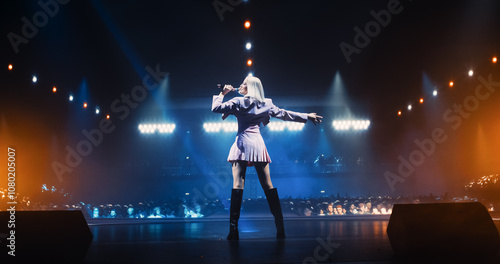 Music Contest: Back View of a Pop Music Artist Performing a Hit Song on Stage in Front of a Sold-Out Audience. Her Charismatic Stage Presence and Lyrics Electrify the Diverse Music Fans