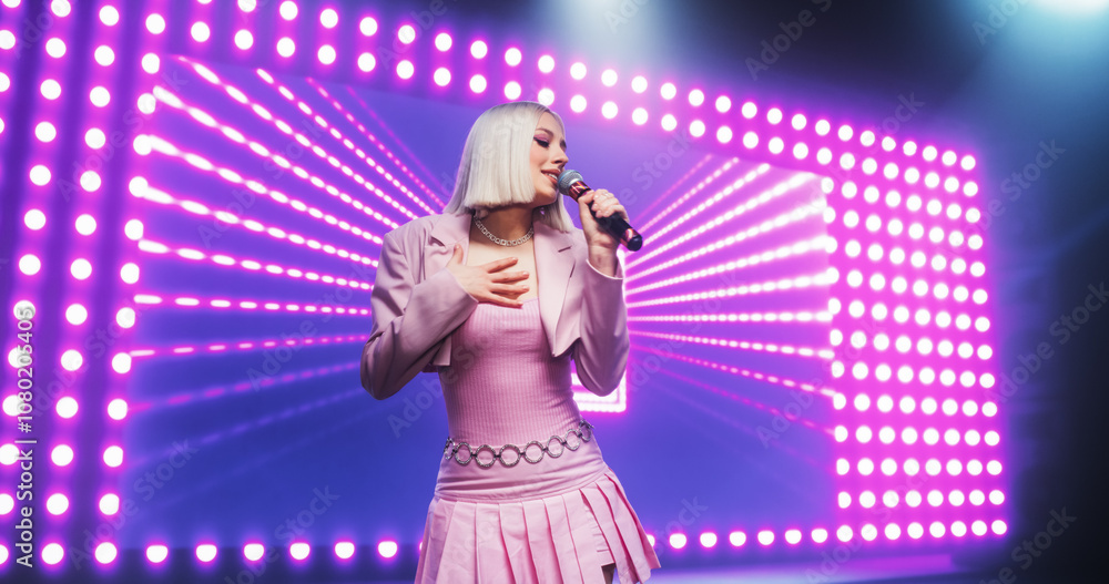 Fans Experiencing a Powerful Musical Performance by a Talented Young Singer. Beautiful Pop Band Lead Singer in Pink Clothes Works on Stage With a Blend of Emotion and Energy, Singing Songs to Audience Fans Experiencing a Powerful Musical Performance by a Talented Young Singer. Beautiful Pop Band Lead Singer in Pink Clothes Works on Stage With a Blend of Emotion and Energy, Singing Songs to Audience