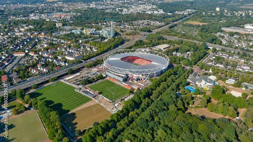 A stunning aerial view of BayArena, Bayer Leverkusen's iconic home stadium, surrounded by lush green landscapes and urban planning in Leverkusen, Germany. Perfect for sports and travel visuals.