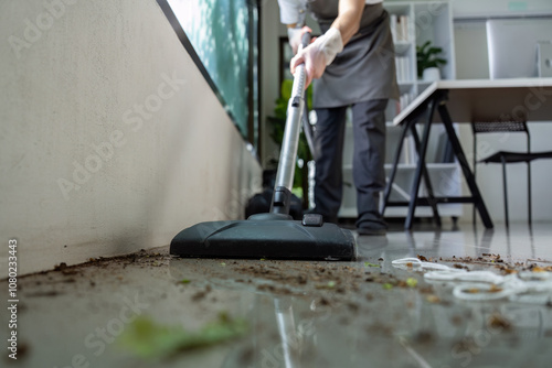 Professional Cleaner Using Vacuum to Remove Dirt from Modern Office Floor with Efficient Cleaning Techniques