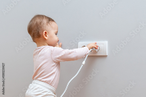 A curious baby explores a plug and outlet, highlighting the importance of childproofing and home safety measures.