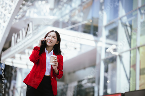 Stylish Asian businesswoman standing confidently in an urban setting holding a tablet. She is dressed in a professional business suit, demonstrating modern leadership and corporate success.