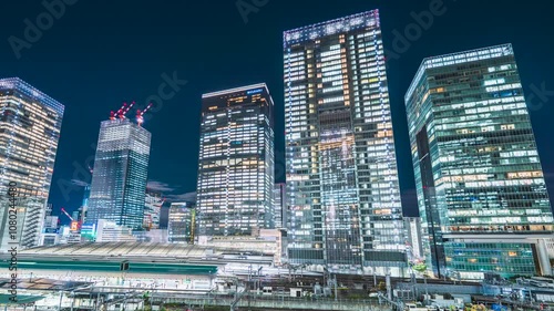 【東京都・中央区】東京・八重洲の超高層ビル群と東京駅を走る電車の光跡　タイムラプス　パンレフト　
The skyscrapers of Yaesu and light trails of train running through Tokyo Station - Tokyo, Japan - Time lapse video - pan left photo