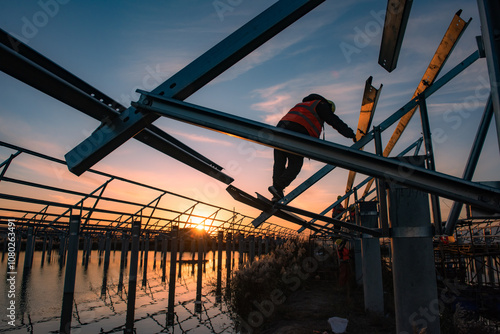 At sunset, workers are installing frames for solar panels at the construction site