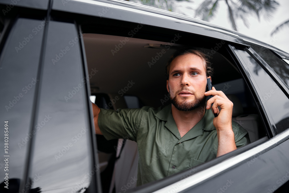 Man talking on the phone from a car window in a green shirt Man talking on the phone from a car window in a green shirt