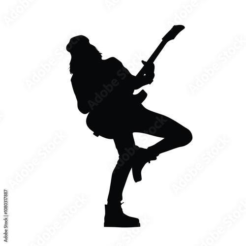 A man in a black shirt and jeans is holding a guitar. He is standing and playing the guitar