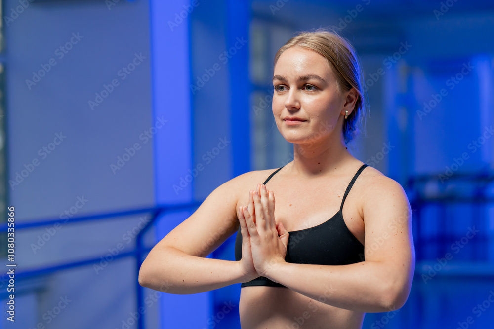 close up in the studio of spiritual development master class in yoga young girl in a black top on purple mat does sits evenly folded palms start of training close up in the studio of spiritual development master class in yoga young girl in a black top on purple mat does sits evenly folded palms start of training