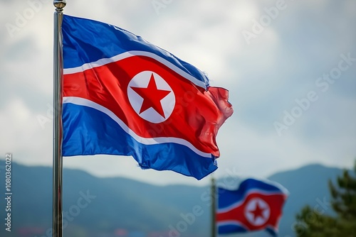 North Korean flags waving in the breeze against a mountainous backdrop on a cloudy day photo