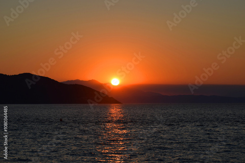 Breathtaking sunset over calm waters, with the golden glow reflecting on the sea surface.