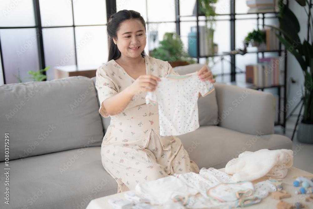 Pregnant asian woman getting ready for the maternity hospital preparing and planning baby clothes for new baby of pregnancy packing baby stuff on bed. Pregnant asian woman getting ready for the maternity hospital preparing and planning baby clothes for new baby of pregnancy packing baby stuff on bed.