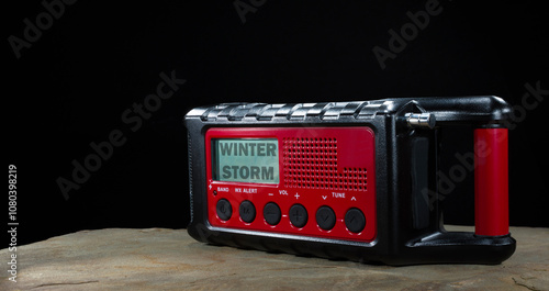 Obraz na płótnie Winter storm watch showing on a weather radio that has a battery backup with small solar panel and a hand crank on a black background. w salonie