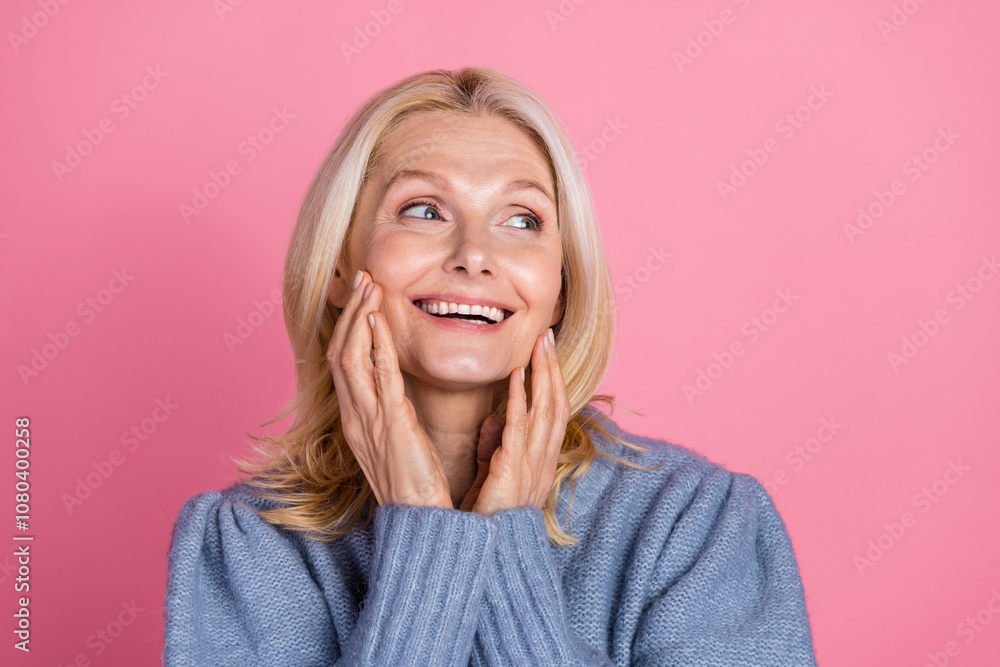 Photo portrait of pretty retired female look empty space touch skin wear trendy blue knitted outfit isolated on pink color background Photo portrait of pretty retired female look empty space touch skin wear trendy blue knitted outfit isolated on pink color background
