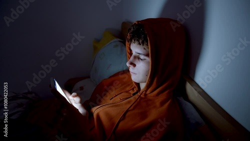 4k medium handheld shot of teenager using a smartphone lying in bed late at night, playing games, watching videos, and scrolling the screen.Children's screen addiction.Screen Addiction in Youth